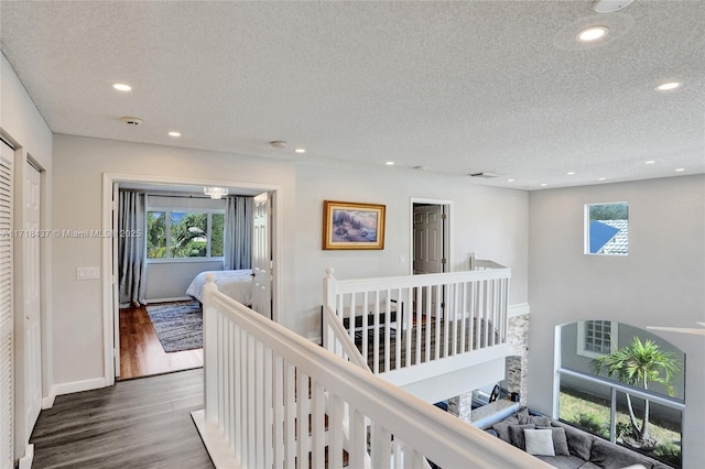 corridor with a textured ceiling and hardwood / wood-style flooring