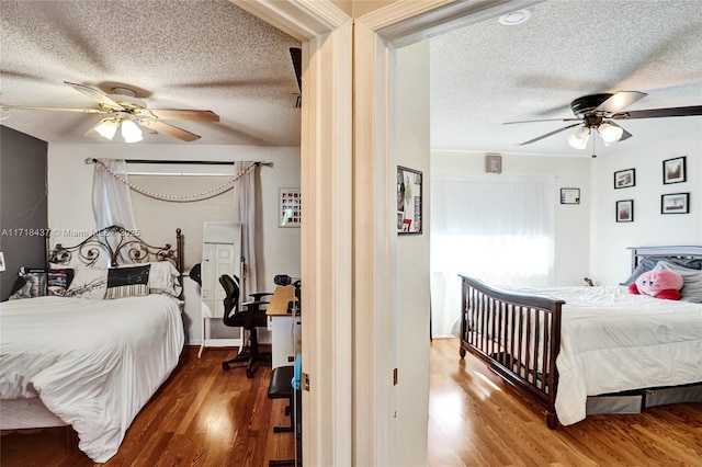 bedroom with ceiling fan, dark wood-type flooring, and a textured ceiling