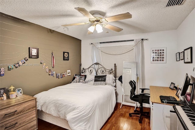 bedroom with ceiling fan, dark wood-type flooring, and a textured ceiling