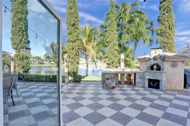 view of patio featuring an outdoor stone fireplace and a water view