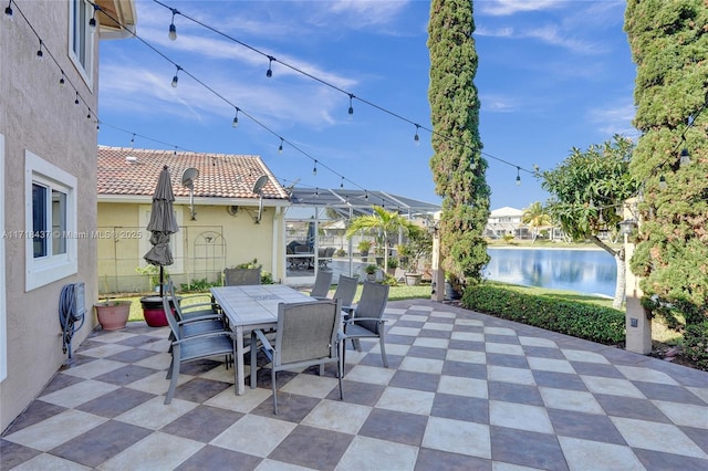 view of patio with a lanai and a water view