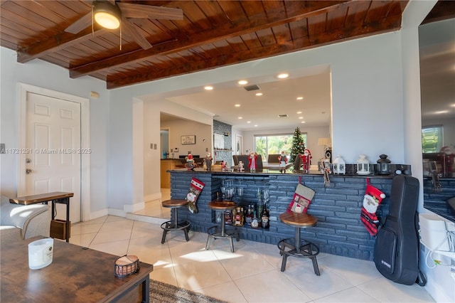 bar featuring beamed ceiling, ceiling fan, light tile patterned flooring, and wood ceiling