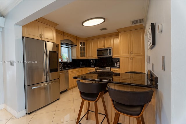 kitchen with kitchen peninsula, appliances with stainless steel finishes, sink, light brown cabinets, and light tile patterned floors