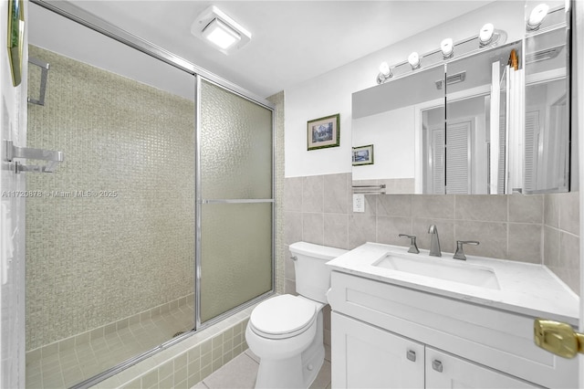 bathroom featuring walk in shower, tile patterned floors, toilet, vanity, and tile walls