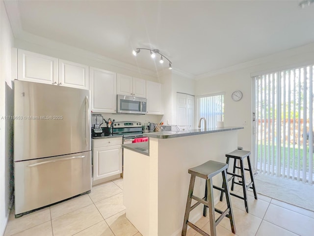 kitchen featuring white cabinets, a breakfast bar, light tile patterned floors, and appliances with stainless steel finishes