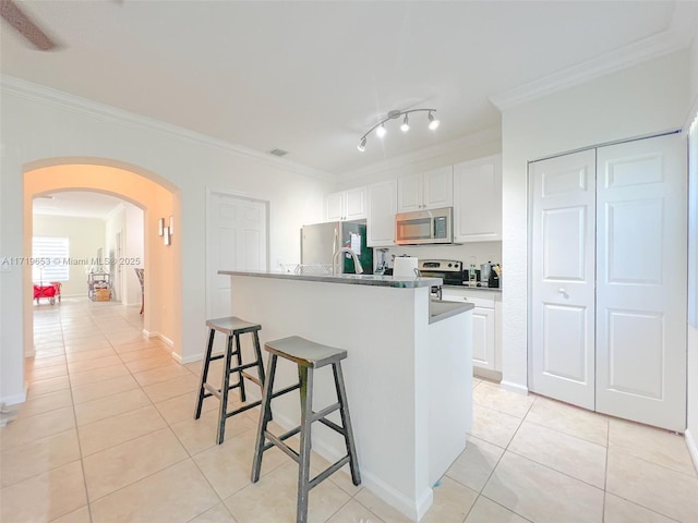 kitchen with appliances with stainless steel finishes, a breakfast bar, crown molding, a center island with sink, and white cabinets