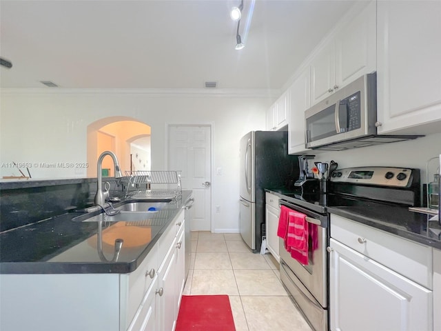 kitchen with white cabinets, sink, light tile patterned floors, ornamental molding, and stainless steel appliances