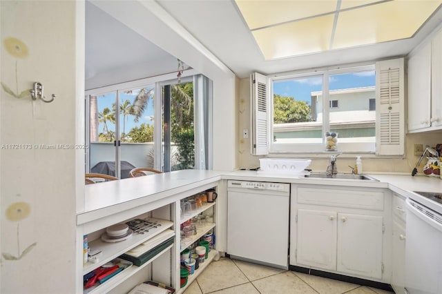 kitchen featuring dishwasher, stove, white cabinets, sink, and light tile patterned floors