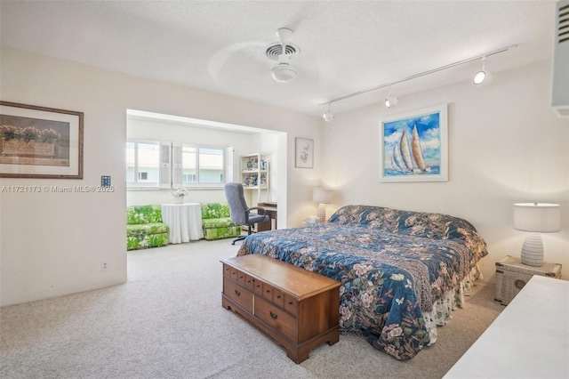 carpeted bedroom with a textured ceiling, ceiling fan, and rail lighting