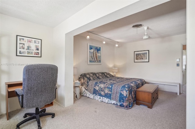 bedroom with light carpet, rail lighting, and a textured ceiling