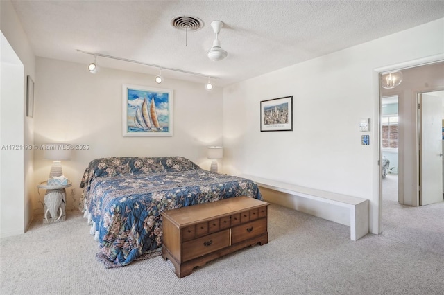 bedroom featuring a textured ceiling, ceiling fan, light carpet, and track lighting