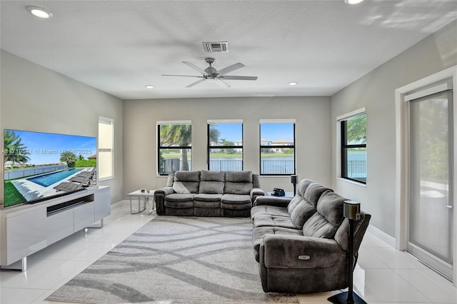 living room with a textured ceiling, ceiling fan, and light tile patterned flooring