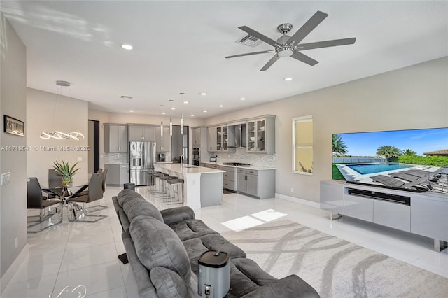 tiled living room featuring ceiling fan and sink