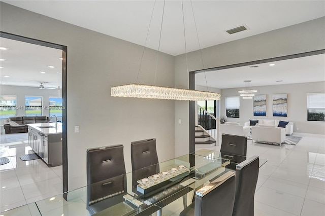 dining space featuring ceiling fan with notable chandelier, sink, light tile patterned flooring, and plenty of natural light