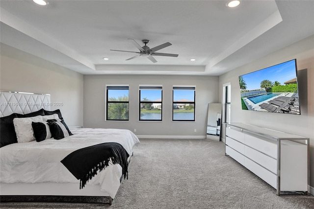 bedroom featuring ceiling fan, a raised ceiling, and light carpet