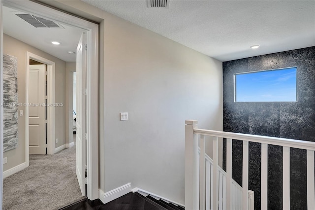 corridor with carpet flooring and a textured ceiling