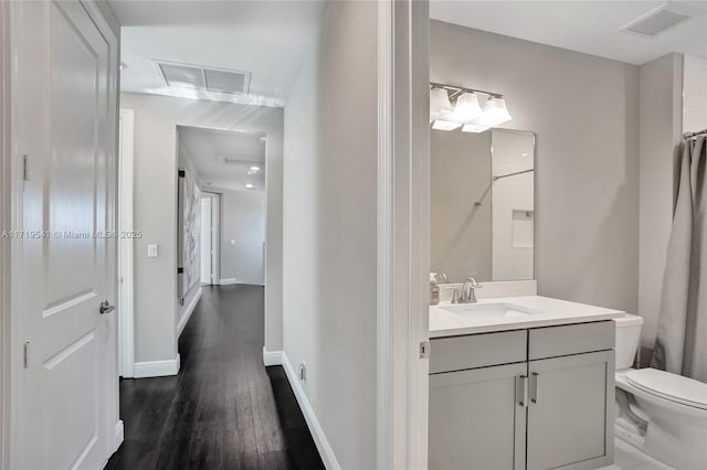 bathroom with hardwood / wood-style flooring, vanity, toilet, and walk in shower