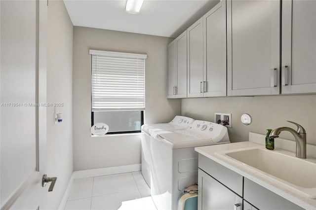 clothes washing area with washing machine and clothes dryer, sink, light tile patterned flooring, and cabinets