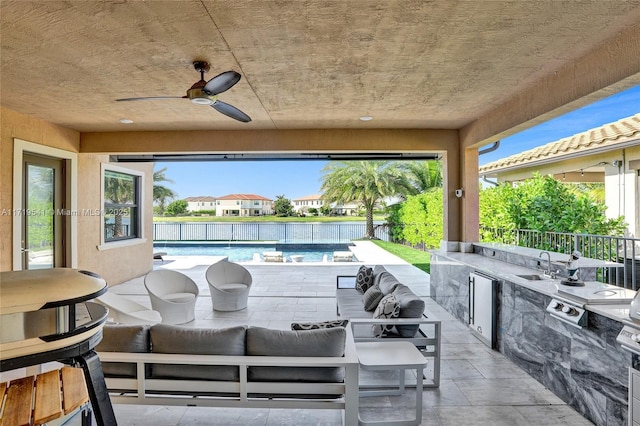 view of patio / terrace with a fenced in pool, an outdoor kitchen, an outdoor hangout area, sink, and ceiling fan