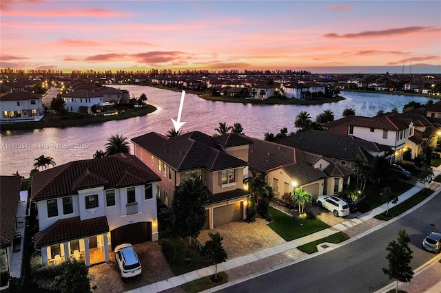 aerial view at dusk featuring a water view