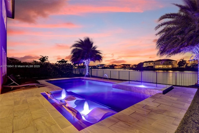 pool at dusk with an in ground hot tub and a patio