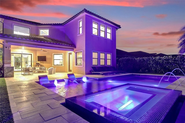 pool at dusk featuring an in ground hot tub, pool water feature, a patio, and ceiling fan