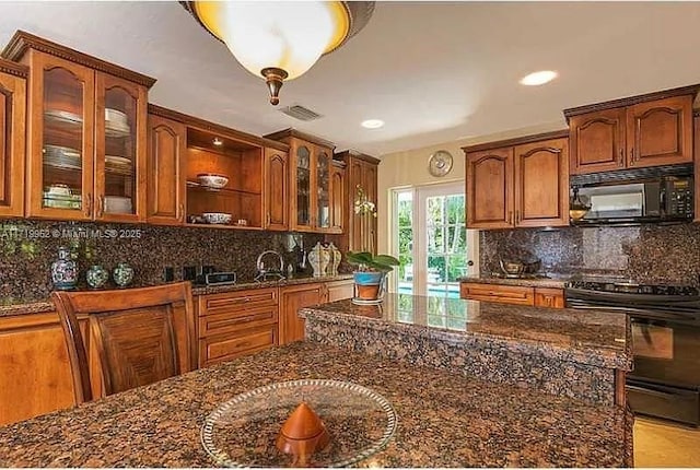 kitchen featuring backsplash, dark stone counters, and black appliances