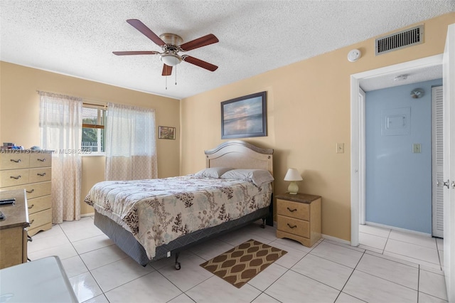 tiled bedroom with ceiling fan and a textured ceiling