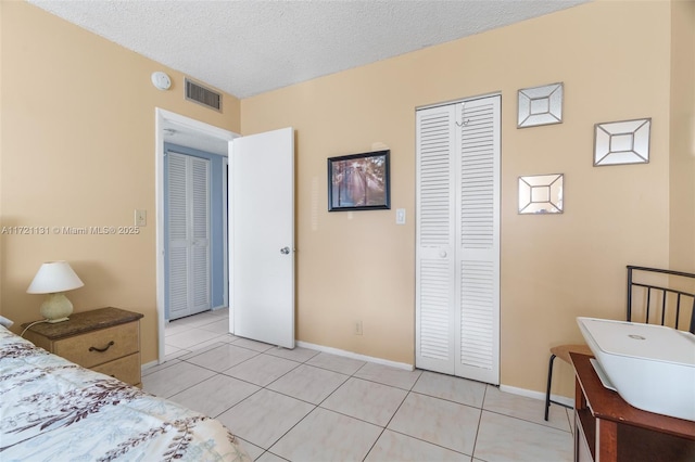 tiled bedroom with a closet and a textured ceiling