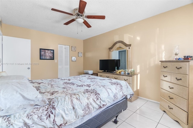 tiled bedroom with ceiling fan and a textured ceiling