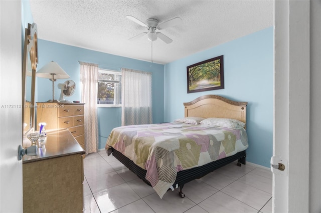 bedroom with a textured ceiling, ceiling fan, and light tile patterned flooring