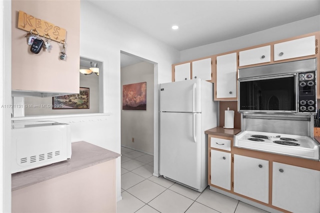 kitchen with light tile patterned floors, white appliances, and white cabinetry