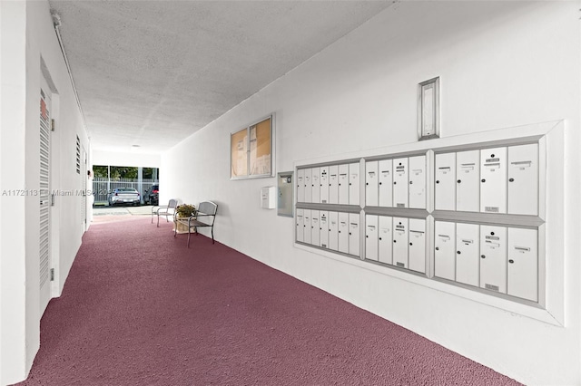 corridor featuring a mail area, carpet, and a textured ceiling