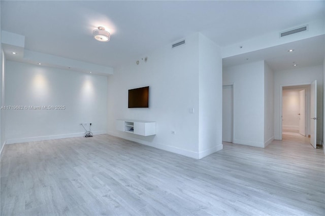 unfurnished living room featuring baseboards, visible vents, and light wood finished floors