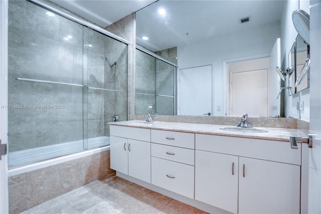 full bath with tile patterned flooring, a sink, tiled shower / bath, and double vanity