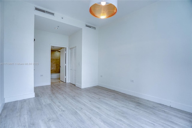 empty room featuring baseboards, visible vents, and wood finished floors