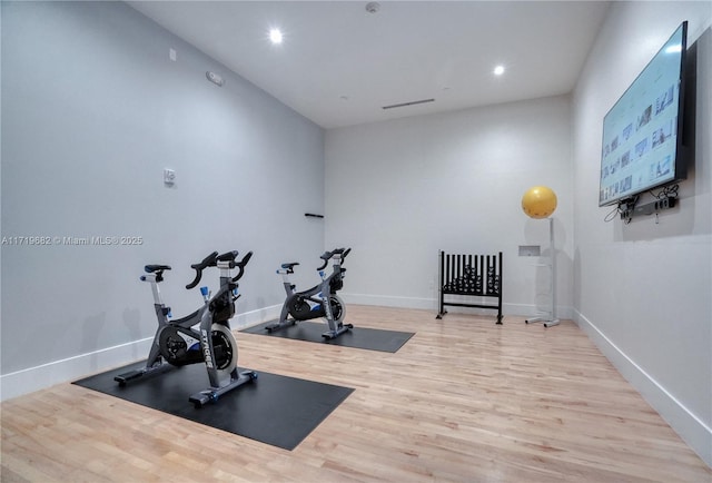 exercise room featuring baseboards, wood finished floors, and recessed lighting