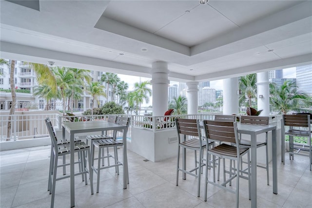 exterior space with a wealth of natural light, a tray ceiling, and ornate columns