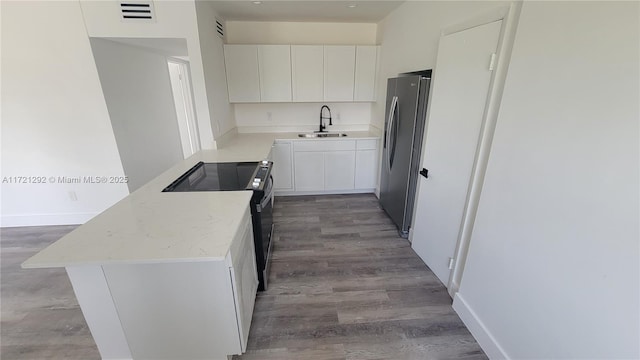 kitchen with hardwood / wood-style floors, sink, black electric range, white cabinetry, and stainless steel refrigerator