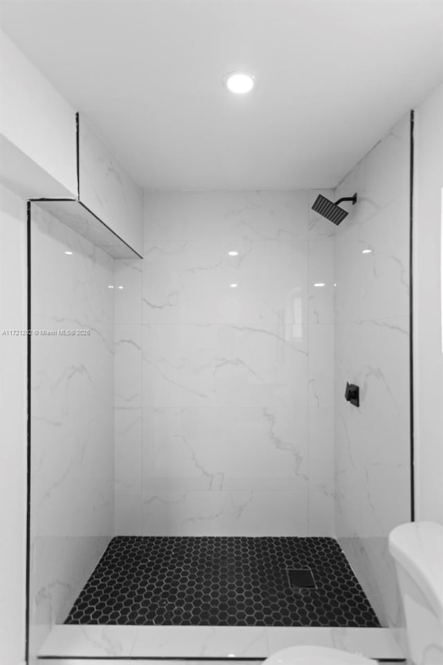 bathroom with a tile shower and toilet