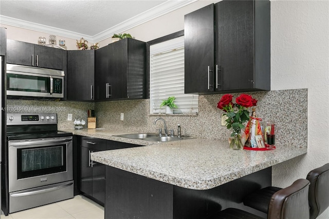 kitchen with a kitchen breakfast bar, ornamental molding, stainless steel appliances, sink, and light tile patterned flooring