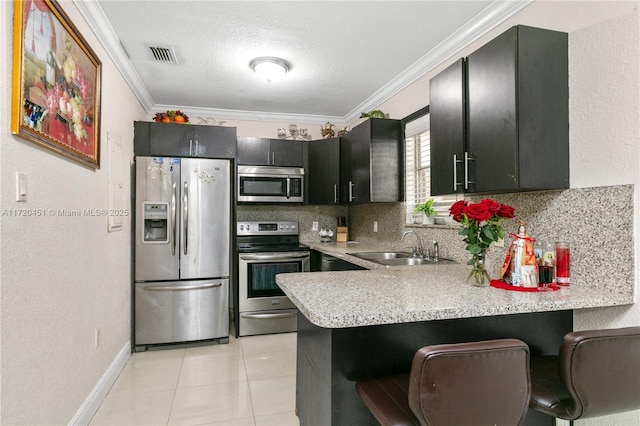 kitchen with sink, kitchen peninsula, a breakfast bar area, light tile patterned floors, and appliances with stainless steel finishes