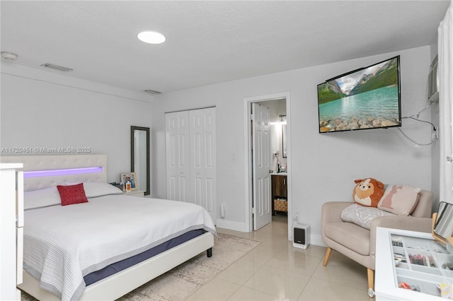 bedroom featuring connected bathroom, a closet, and light tile patterned floors