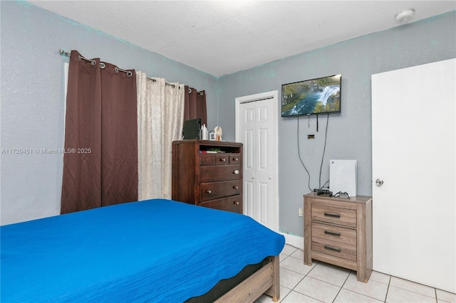 bedroom featuring light tile patterned flooring, a textured ceiling, and a closet