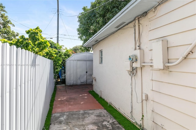 view of side of home with a storage unit and a patio area