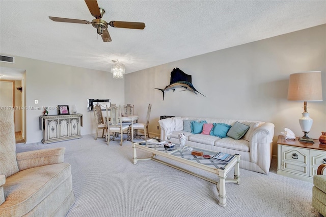 living room featuring ceiling fan, carpet floors, and a textured ceiling