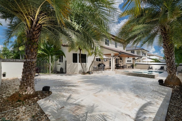 exterior space with ceiling fan, a patio area, and a pool with hot tub