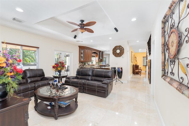 living room with ceiling fan and a tray ceiling