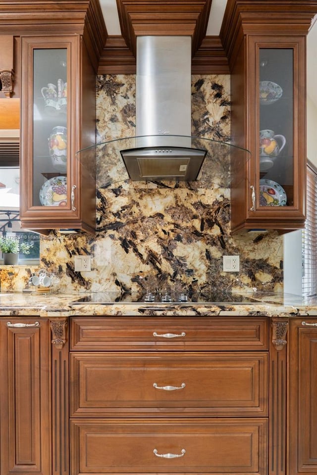 kitchen with light stone counters, wall chimney range hood, and tasteful backsplash