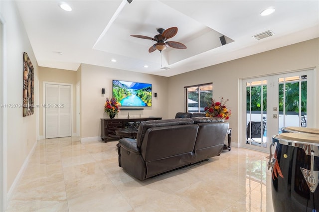 living room featuring french doors, a tray ceiling, and ceiling fan